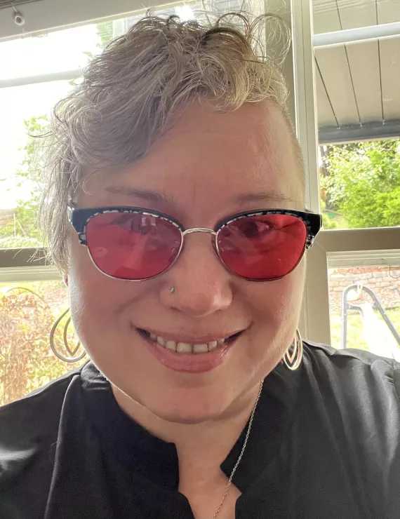A picture of a white woman with short haircut in colored glasses