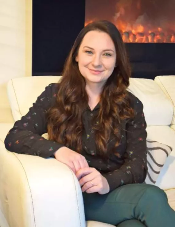 photo of female therapist sitting on couch with fireplace in background