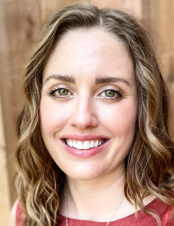 Image of a white woman's face smiling with wavy hair and kind eyes. 