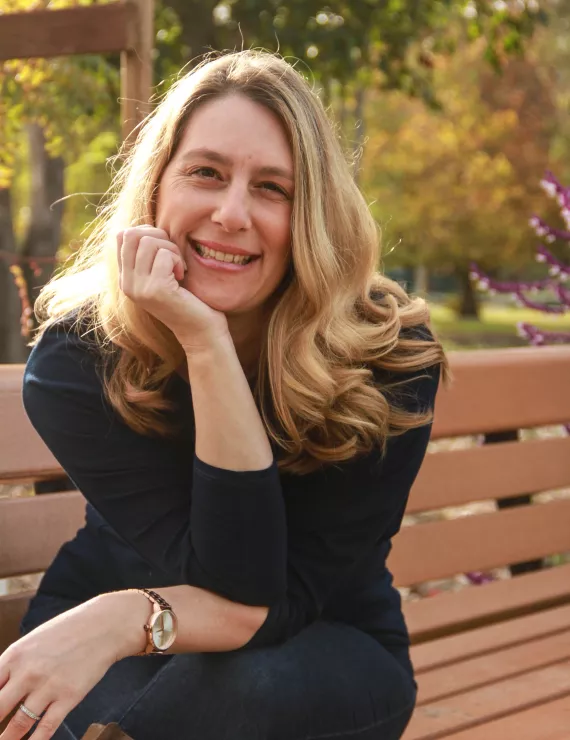 Rebecca smiling on a bench.