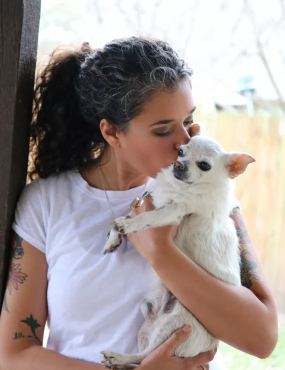 An image of Rebecca kissing an elderly white chihuahua. 