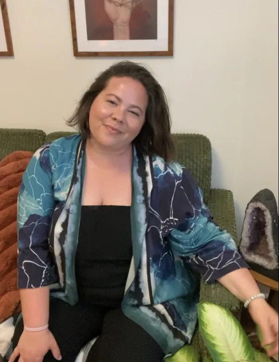 Photo of woman sitting on green couch with plants and crystals