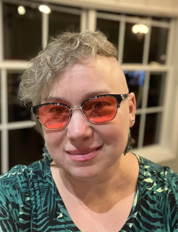 Picture of a white woman in colored glasses and green dress