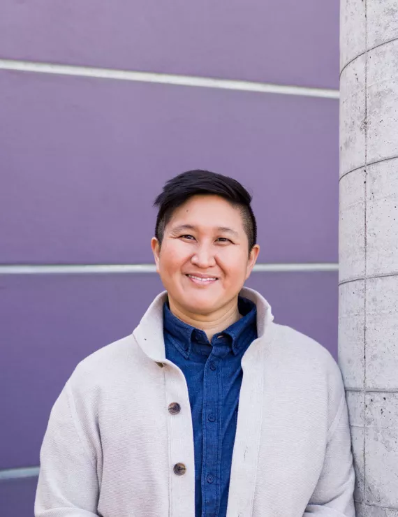Asian nonbinary person with short black hair against purple background